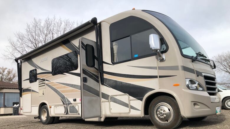 A brown and black RV is parked in an outside lot. 