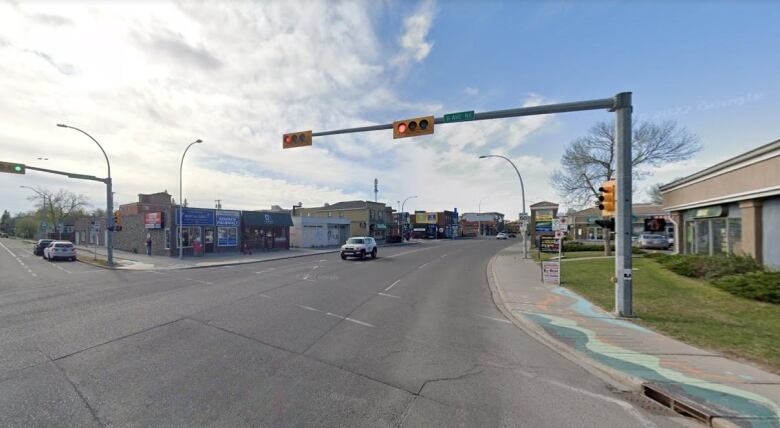 An intersection with traffic lights surrounded by low-rise commercial buildings.