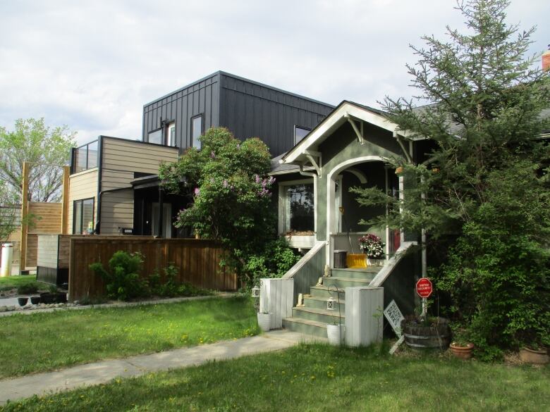 Two homes on a street next to a sound wall. 