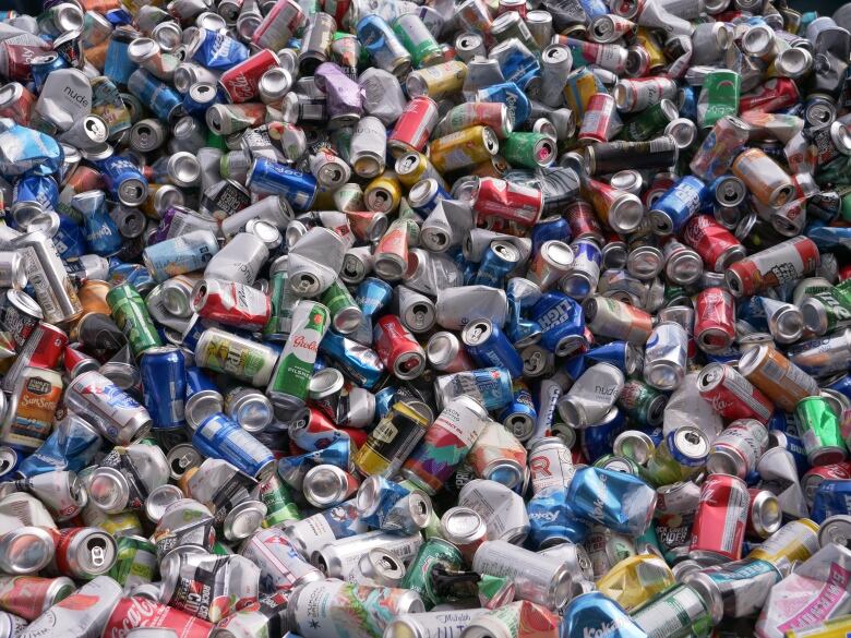 An array of colourful pop cans in a pile.