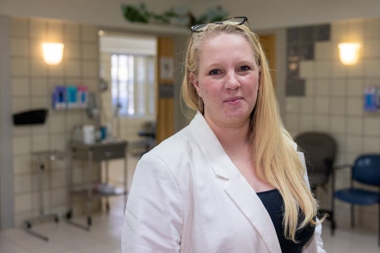 A woman with long blonde hair wearing a white lab coat is seen in a clinician's office