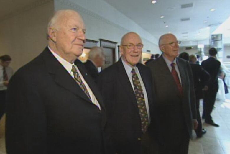 Three men stand next to each other