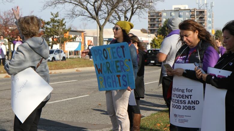 Vanessa Vella standing on the side of the road with a sign that reads 