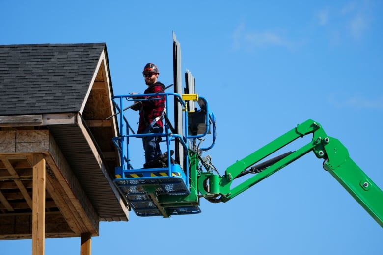 A construction worker works from a lift on a house