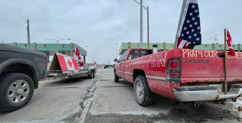 A red pick up truck with American flags and black pick up trick with Canadian flags. 