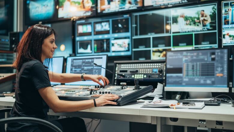 Woman seated at a control board.