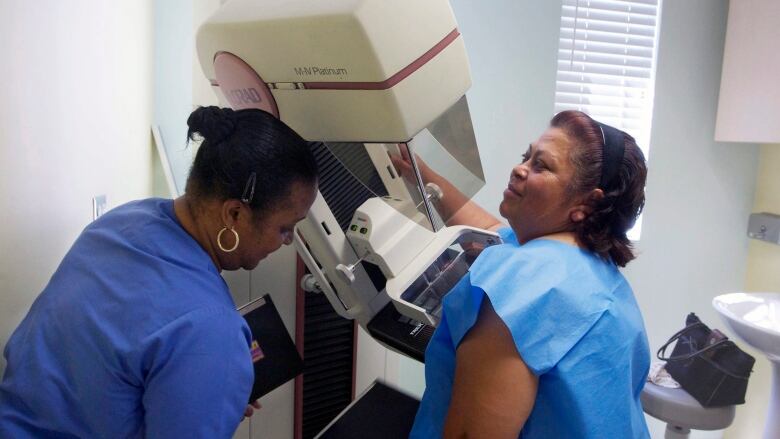 A woman receives a screen-film mammography. 