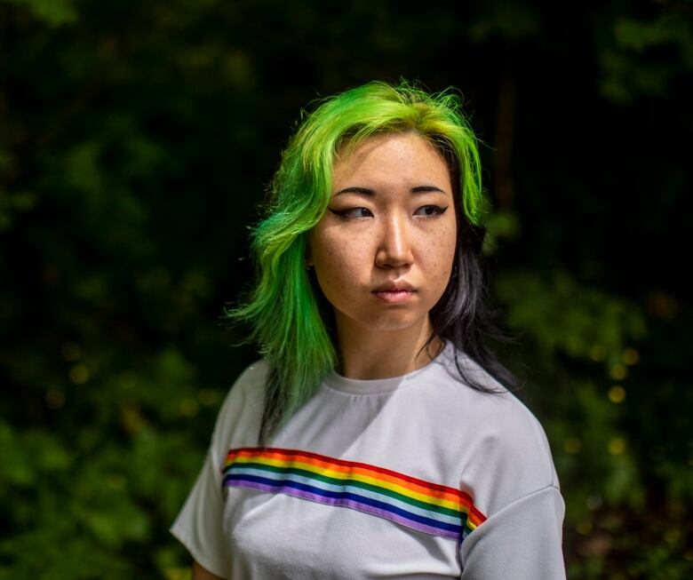 A photo of Mona Wang, a young woman with dyed green and purple hair, looking off camera