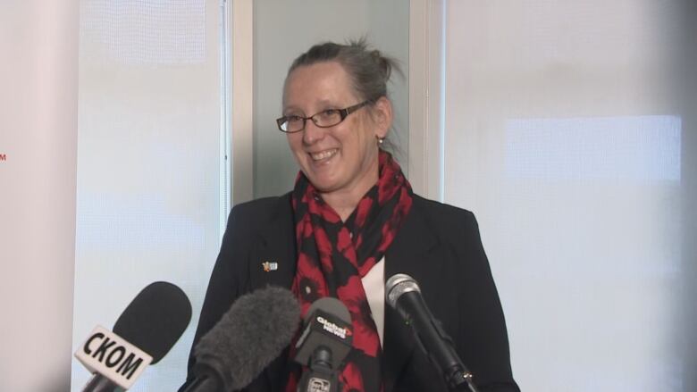 A lady with a poppy flower scarf smiles.