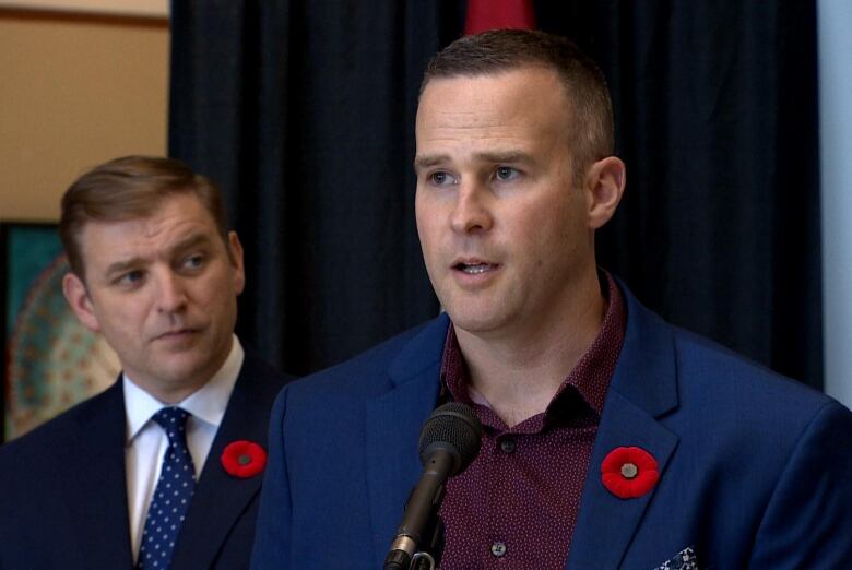 A man in a suit stands at a microphone