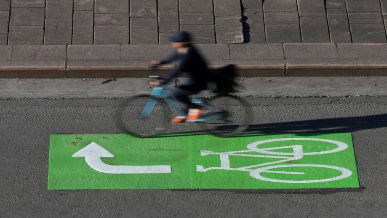 A cyclist crosses a green painted bike box with an arrow pointing right.