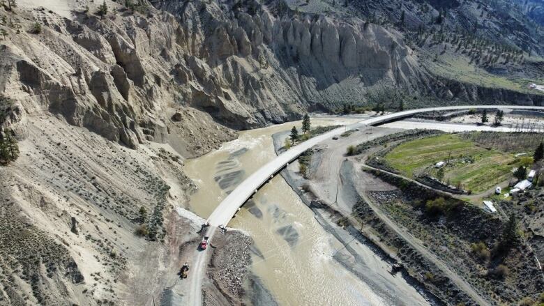 An aerial shot of a highway framed by cliffs with embankments running down to the road.