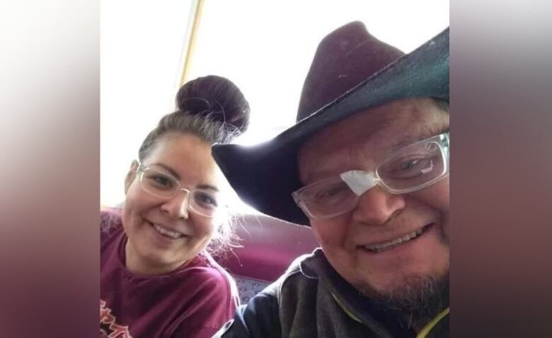 A woman with glasses poses with an older man with glasses and a cowboy hat.