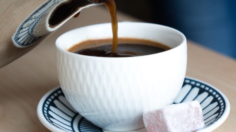 A cup of coffee with a candy beside it.