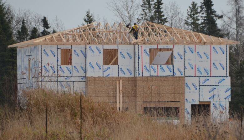 Two men stand on the roof of a house under construction in the Hanmer area of Greater Sudbury