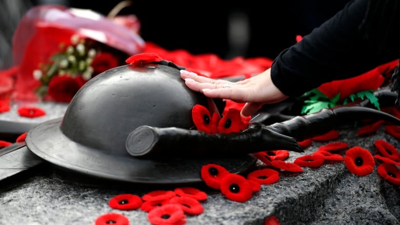 A helmet on ground surrounded by red poppies.