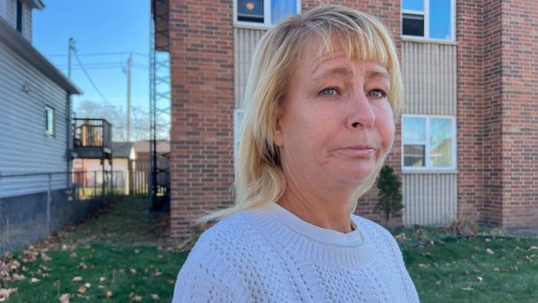 Woman stands in front of an apartment building.