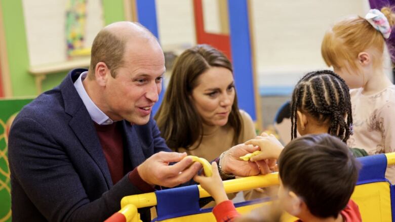 Two adults play with modelling dough with three children.