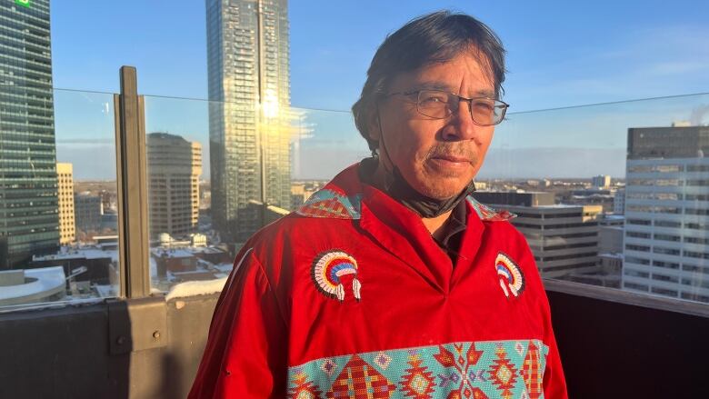 A man in a red sweater is seen on a snowy balcony in downtown Winnipeg.