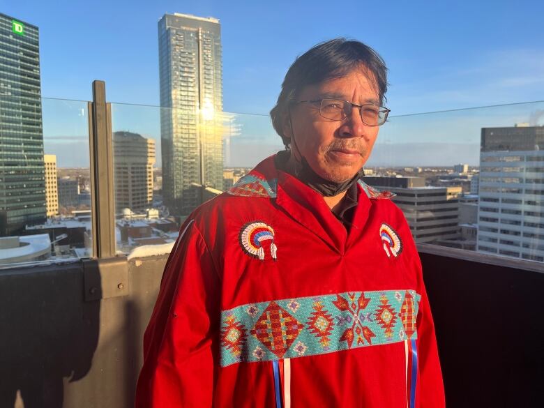 A man in a red sweater is seen on a snowy balcony in downtown Winnipeg.