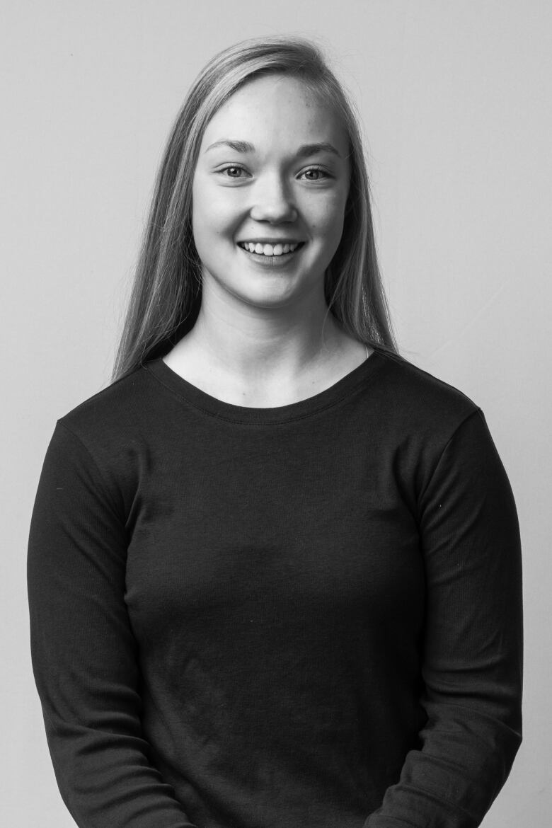 A young fair-haired woman smiles at a camera in a black-and-white photo.