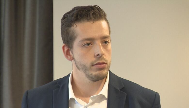 Man looking slightly off camera wearing white shirt and navy blazer.