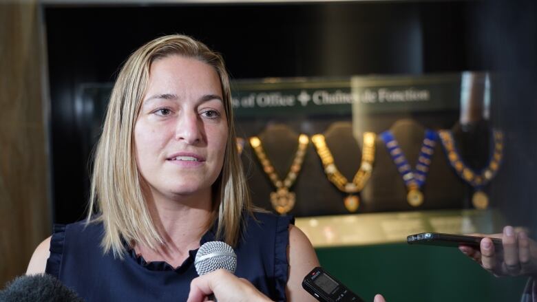 A woman speaks into an interviewer's microphone.