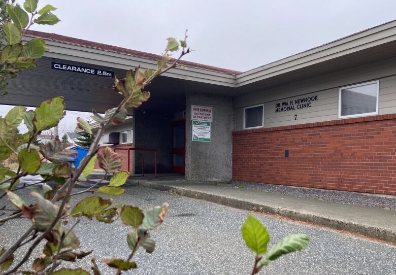 A photo of the exterior of a red brick building with and overhang and concrete pillars. It is the Dr. William H. Newhook Health centre in Whitbourne.