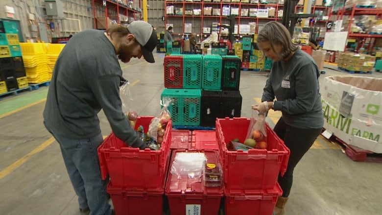 Two people sort groceries in a warehouse. 