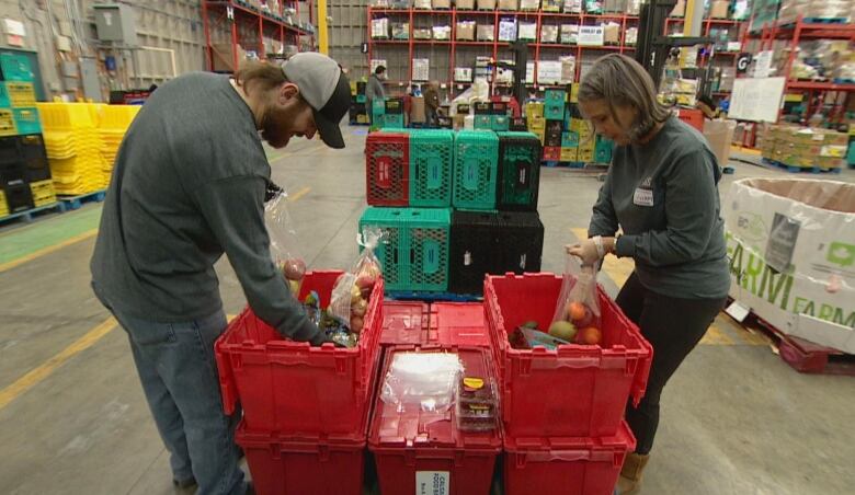 Two people sort groceries in a warehouse. 