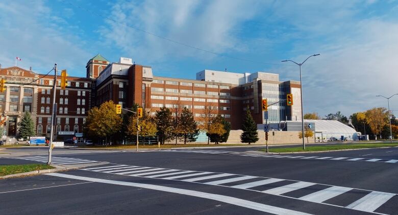 An empty crosswalk in front of a hospital building on a clear day.