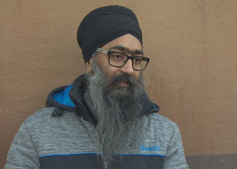 A Sikh man wearing a turban looks at the camera.