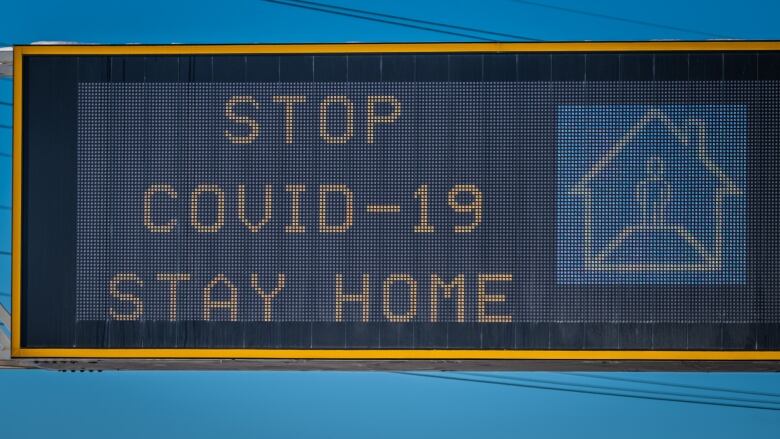 'STOP COVID-19, STAY AT HOME' overhead sign on a highway.