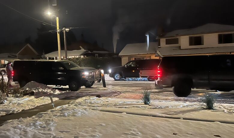 A series of police vehicles on a snowy suburban street.