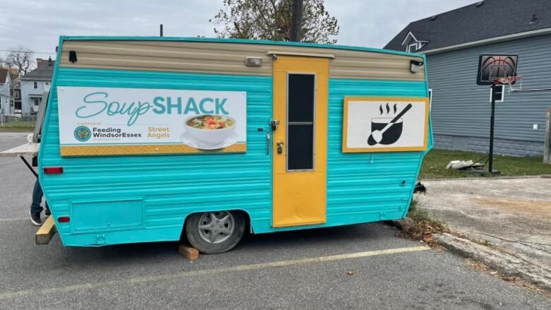 A small camper has bright blue and yelow paint with a sign that says Soup Shack. 