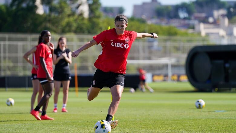 A female soccer player is seen winding up for a kick on a soccer pitch.