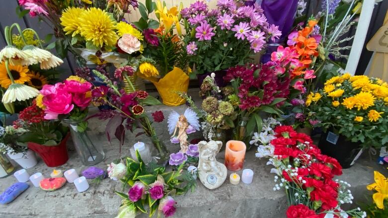 An arrangement of flowers and candles on a concrete step.