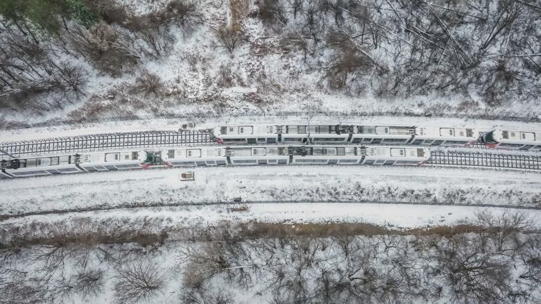 From above, two white trains pass each other in the snow.