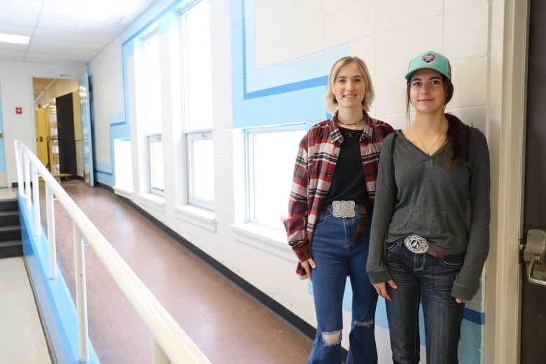 Two friends stand in their school's hallway.