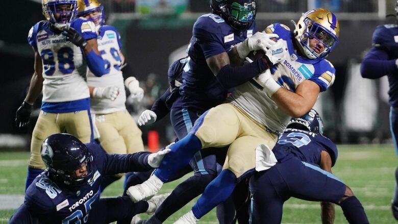 A group of professional football players battle for the ball.