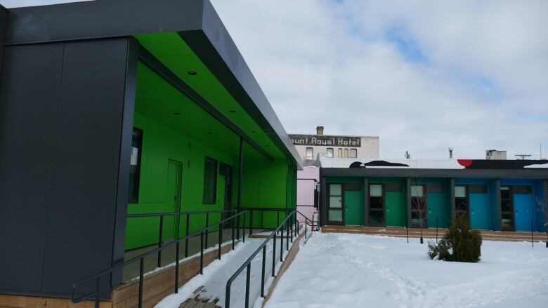 A row of houses with green and blue doors is shown in this picture.