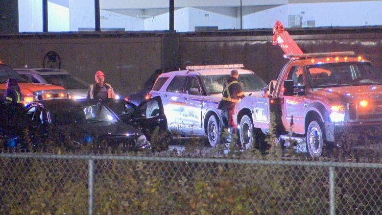 A tow truck and a police vehicle can be seen at one of multiple crime scenes after a robbery and police chase in Coquitlam, B.C., on Nov. 22, 2022.