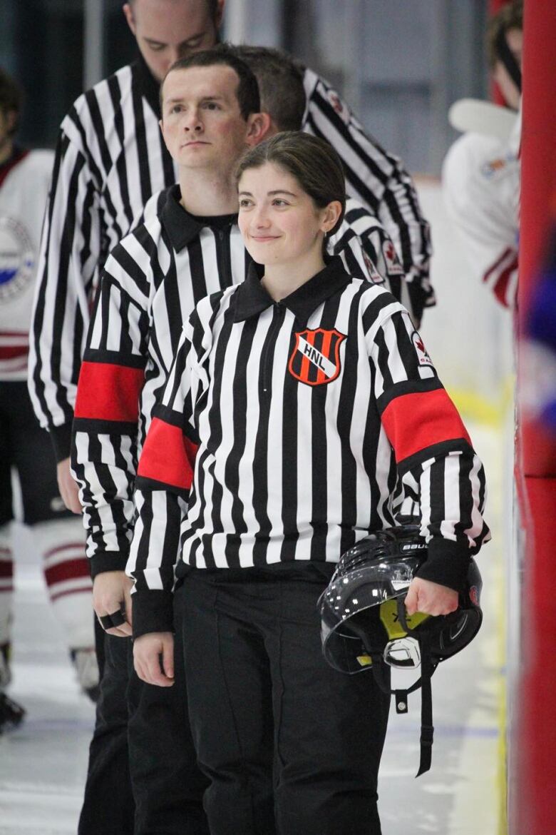 A line up of hockey referees standing on the ice. 