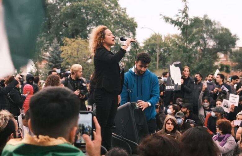 A woman speaks into a microphone at a protest.