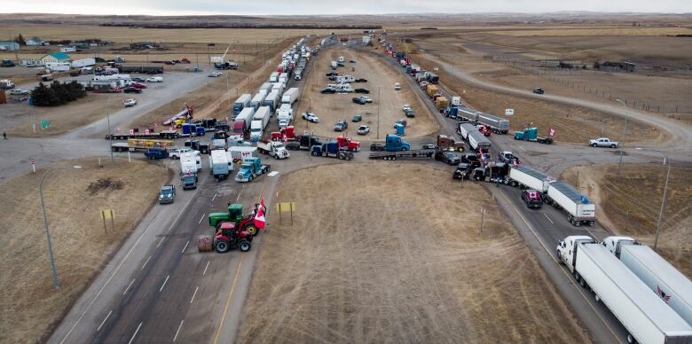 Long lines of semi trucks point in either direction on a divided highway.