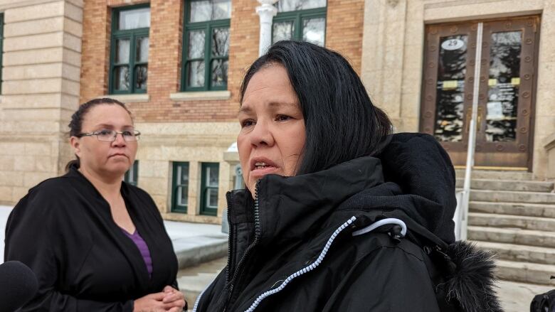 two women stand outside a courthouse in winter