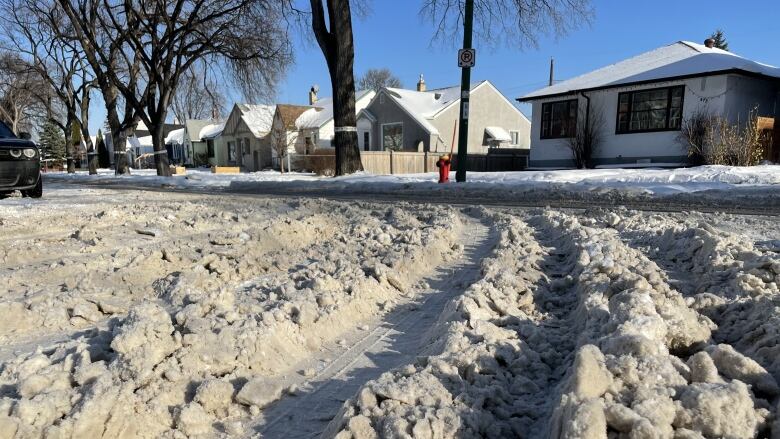 Winnipeg residential street full of snow and tire ruts. 