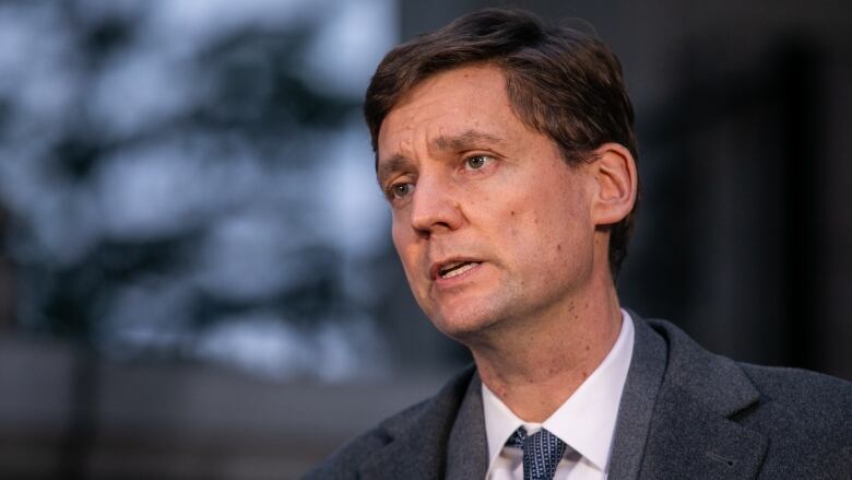 David Eby, a white man wearing a suit, speaks at a news conference.