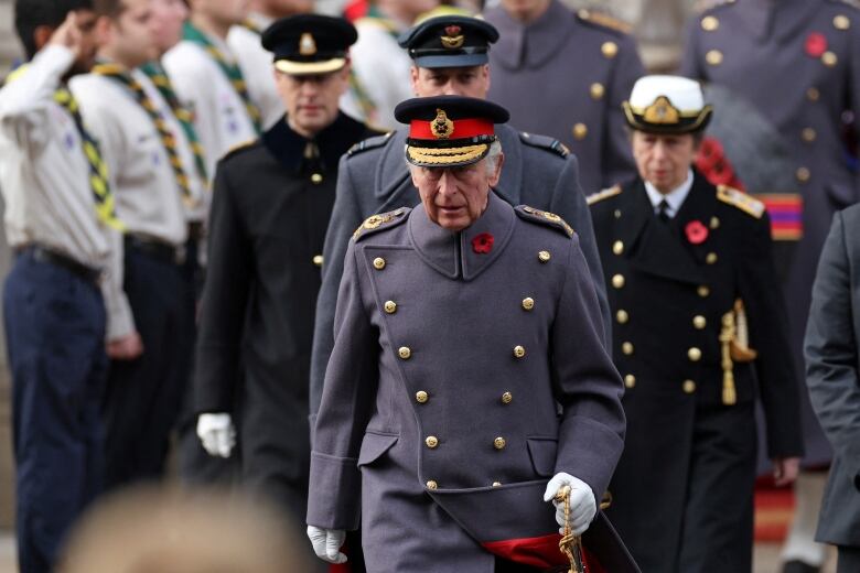 Four people walk in line in for a remembrance ceremony.