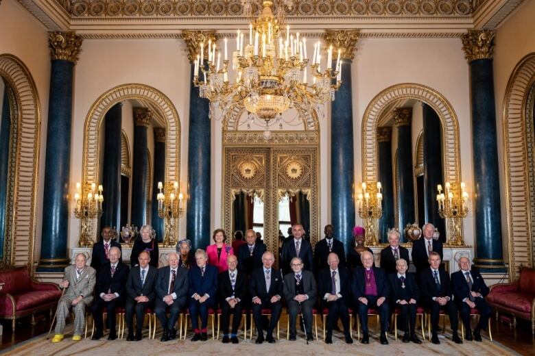 A large group of people in a room with a large chandelier hanging from the ceiling.